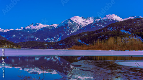 Phalanx Mountain reflected in portion of Green Lake, Whistler, BC, not covered in ice - viewed from Valley Trail, late winter