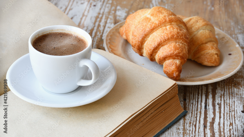 Сup of coffee and croissant on a wooden table Сup of coffee and croissant on a wooden table