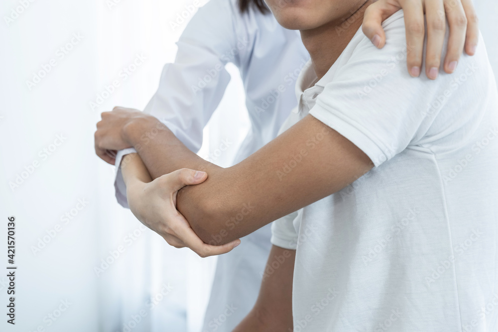 Female doctor hand doing physical therapy By extending the shoulder of a male patient