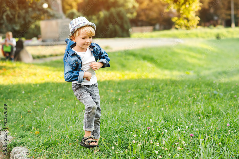 Stylish little boy posing at summer park. Fashion, lifestyle and summer concept. Stylish little boy posing at summer park. Fashion, lifestyle and summer concept.