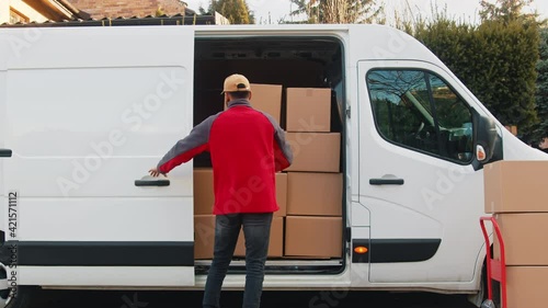 Young delivery man putting parcel into the van. Delivery during covid outbreak. High quality 4k footage