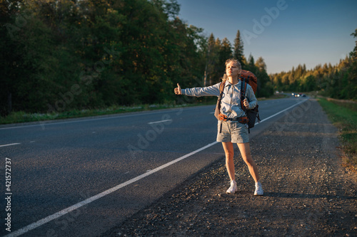 Travel woman with backpack hitchhiking on road