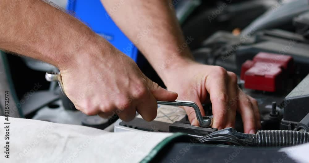 Auto mechanic worker checking and changing car battery. Car maintenance and auto service garage concept. Auto mechanic worker checking and changing car battery. Car maintenance and auto service garage concept.