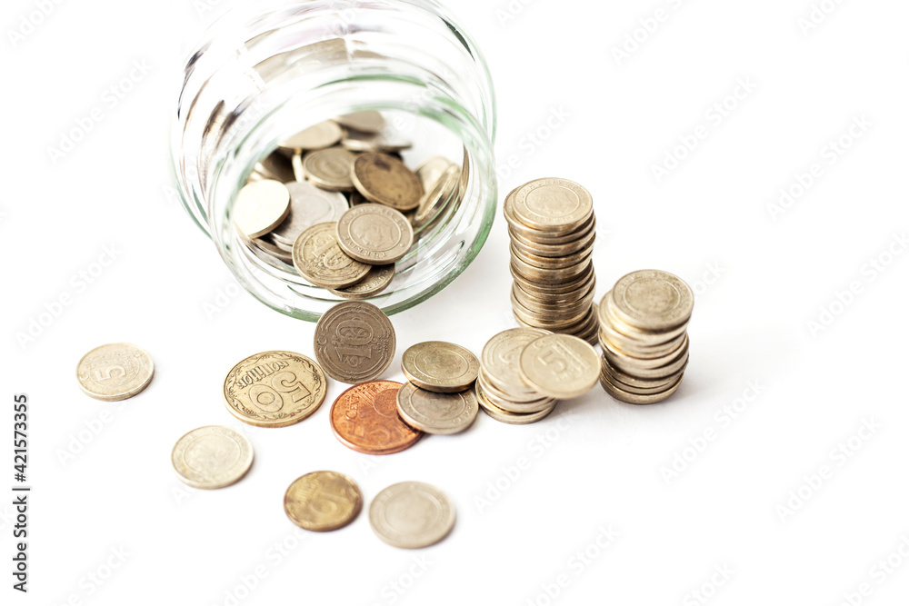 Overturned glass jar full of shined Golden coins on the white background Overturned glass jar full of shined Golden coins on the white background