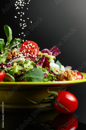 Green salad with greens, tomatoes, walnuts and vegetable oil sprinkled with sesame.