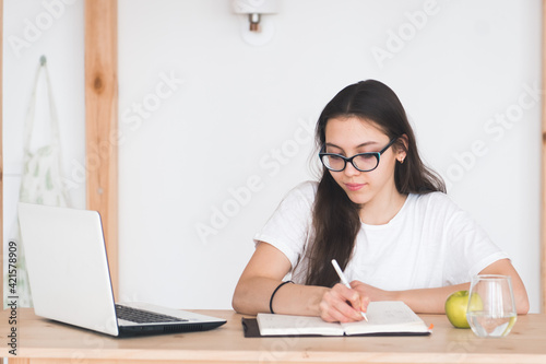 Young girl student doing homework with laptop at home, online learning, distance education