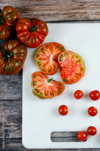 Vertical shot of Brandywine and cherry tomatoes on cutting board photo