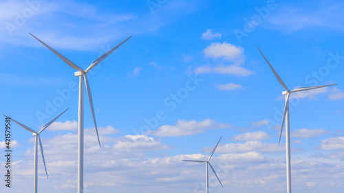 Electric wind turbine with blue sky and clouds.