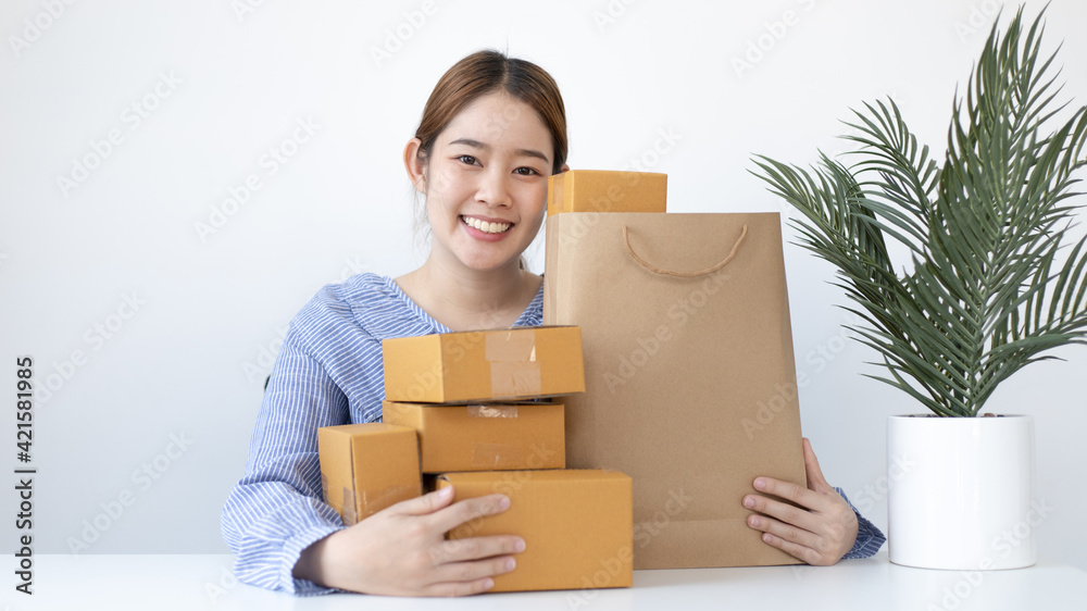 Young woman embraced a mailbox and a brown paper bag in preparation for the delivery of her order, New business style for young people working at home and owning businesses, Sell online concept. Young woman embraced a mailbox and a brown paper bag in preparation for the delivery of her order, New business style for young people working at home and owning businesses, Sell online concept.