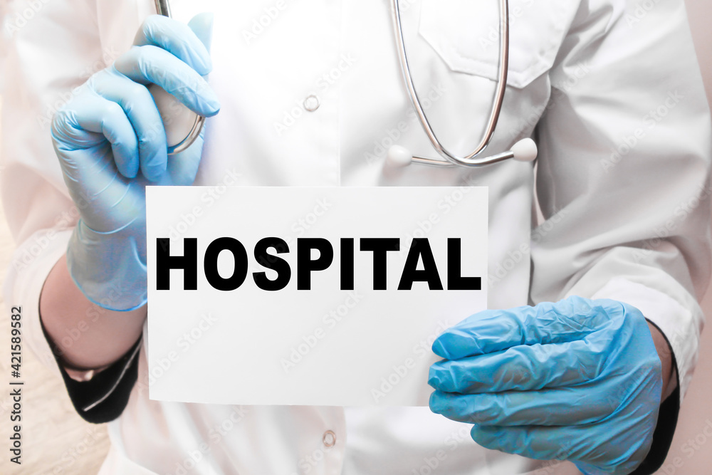 The doctor's blue - gloved hands show the word HOSPITAL - . a gloved hand on a white background. Medical concept. the medicine The doctor's blue - gloved hands show the word HOSPITAL - . a gloved hand on a white background. Medical concept. the medicine