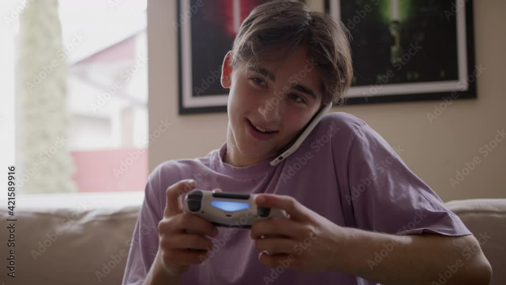Beautiful Excited Young Gamer man Sitting on a Couch, Playing and Winning in Video Games on a Console. He Plays with a Wireless Controller Beautiful Excited Young Gamer man Sitting on a Couch, Playing and Winning in Video Games on a Console. He Plays with a Wireless Controller