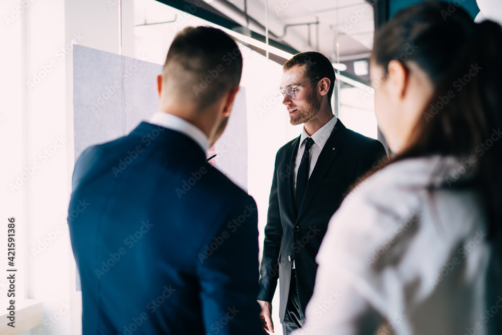 Fototapeta premium Positive colleagues discussing business near office glass wall