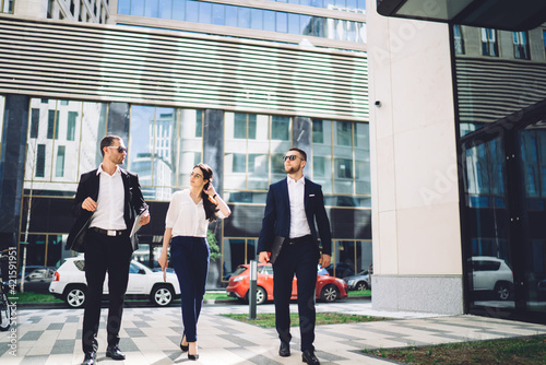 Young colleagues walking along on street near modern office building
