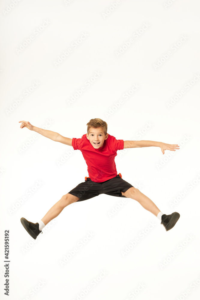 Cheerful cute boy in sportswear jumping in studio