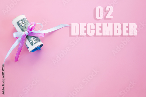 calendar date on pink background with rolled up dollar bills pinned by pink and blue ribbon with copy space.  December 2 is the second  day of the month