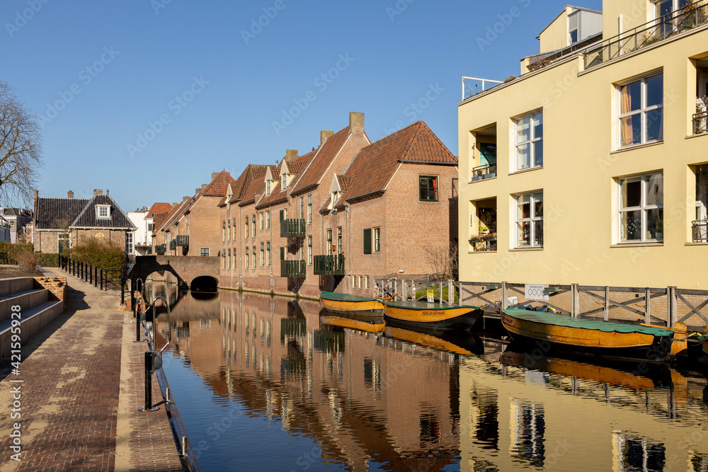 Historic facades of medieval city Zutphen in The Netherlands with whisper boats reflected in the water of river Berkel against a clear blue sky