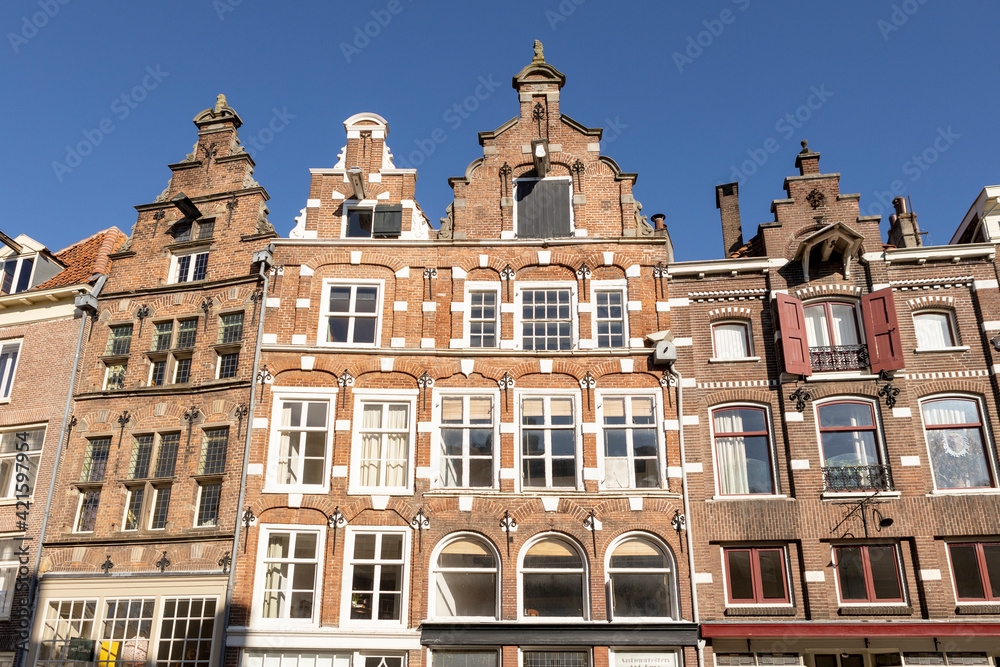 Bright historic medieval exterior facades of Hanseatic city center Zutphen in The Netherlands against a clear blue sky.
