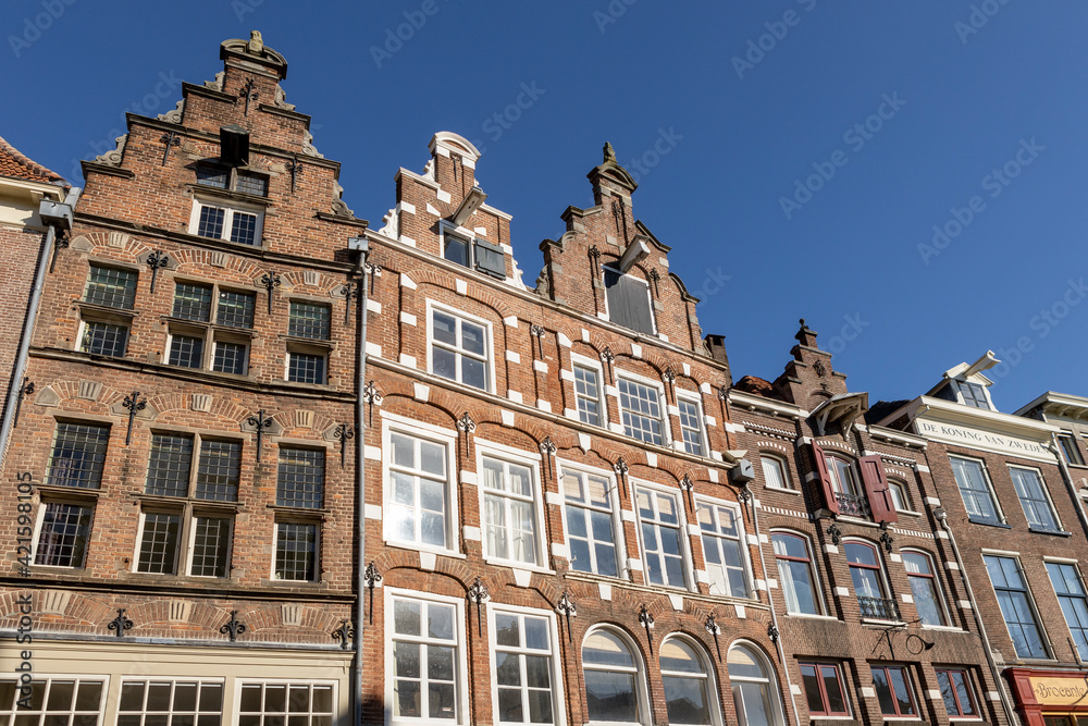 Looking up at typical historic medieval exterior facades in Hanseatic city center Zutphen, The Netherlands, against a clear blue sky. Europe tourism destination.