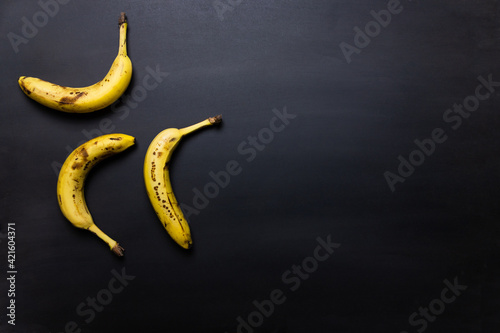 Three ripe bananas on black background