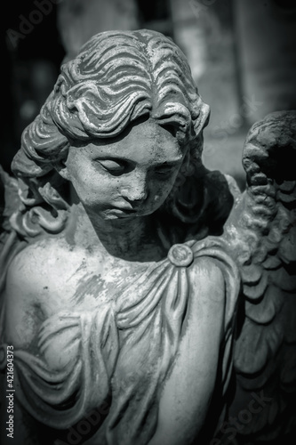 Close up sad angel. Fragment of ancient statue. Vertical image. Death, pain concept.