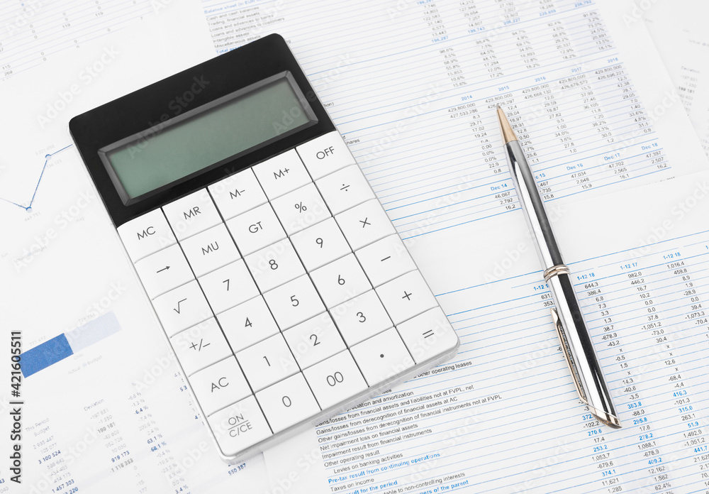 Financial charts and a calculator on the accountant's desk. Calculating profits, taxes, and paying employees salaries. Financial charts and a calculator on the accountant's desk. Calculating profits, taxes, and paying employees salaries.
