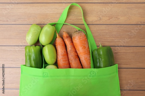 Vegetables in Eco bag on wooden background, with copy space. Groceries in Reusable Green Bag.