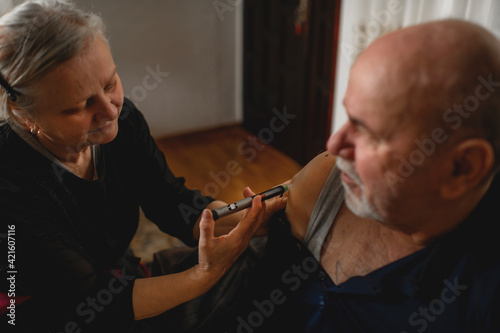 Senior woman giving insulin her diabetic husband at home