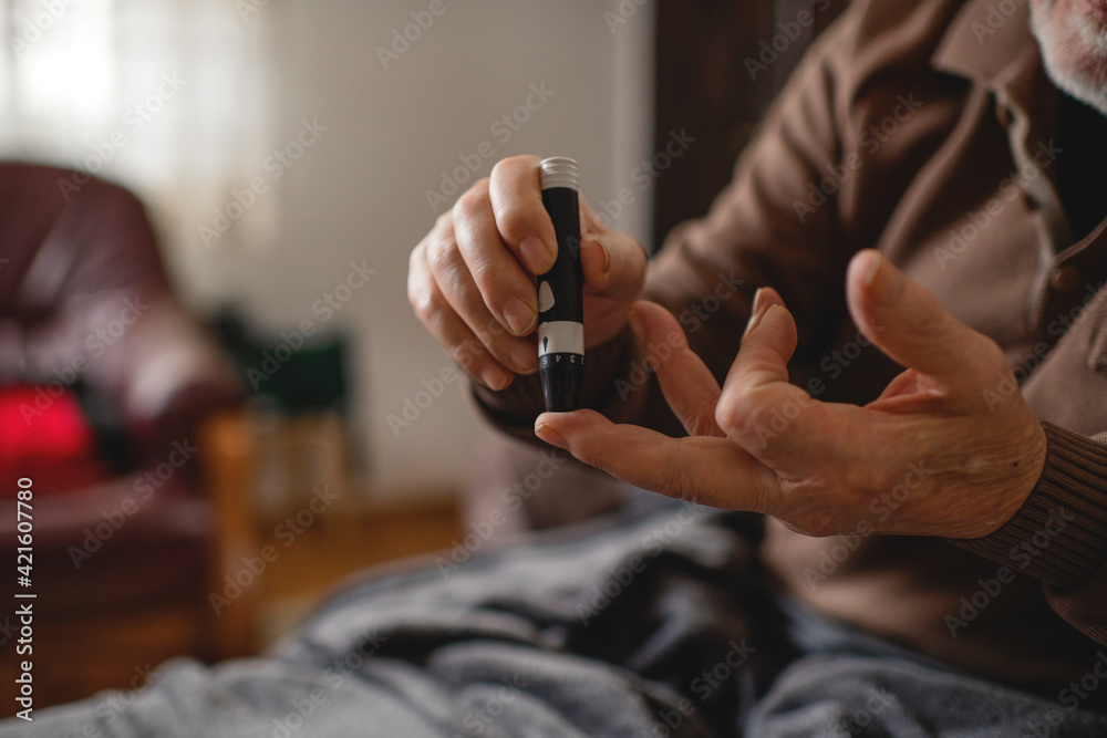 Senior men with glucometer checking blood sugar level at home