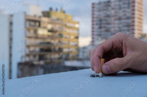 hand extinguishing cigarette with view of the city. anti-smoking day. may 31