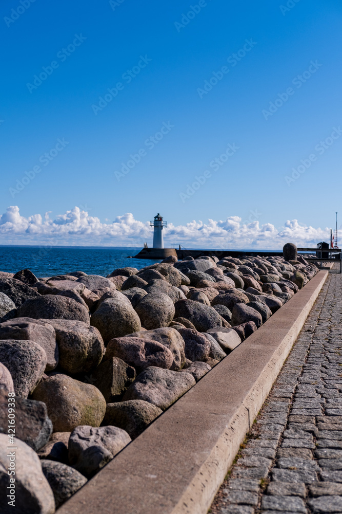 Rocky man made path leding to lighthouse in the middle of water at Hjo, Sweden