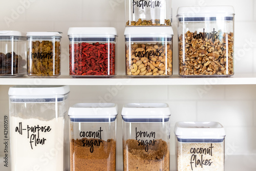 Baking ingredients in BPA-free plastic storage containers with labels in an organized kitchen pantry
