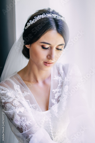 A woman in a white robe, perfect skin, hair. A girl with a stylish hairstyle. Morning preparations. Close up of young gorgeous bride