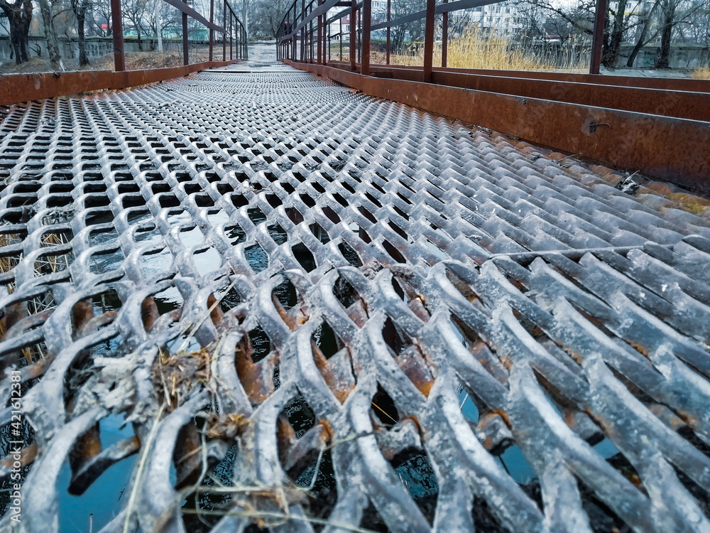 Metal lattice structural  bridge over the river, view from below, symmetrical lines leading into the distans. - obrazy, fototapety, plakaty 
