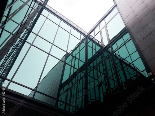 Modern architecture, a fragment of a building made of glass and concrete, reflections in the glass facade.