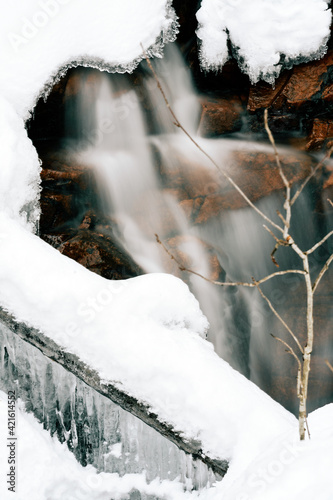 Ice under snowy river. Waterfall under the cracks in a icy river. 