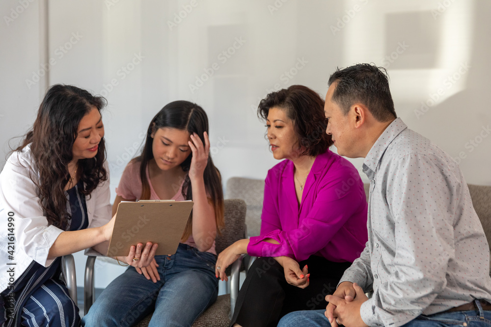 Doctor explains form to Asian family in waiting room Doctor explains form to Asian family in waiting room