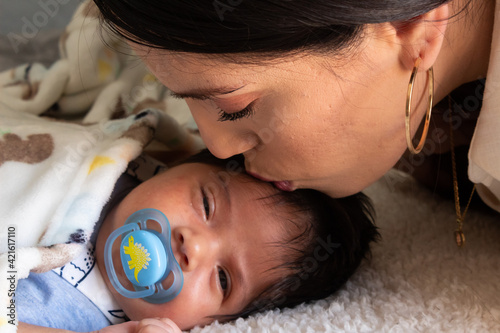 beautiful portrait of a young hispanic mother with her newborn baby