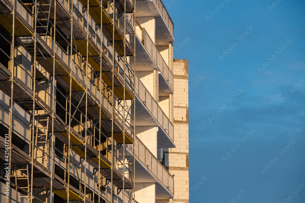 Fototapeta premium Metal-wood scaffolding on the facade of an apartment building against the sky outside