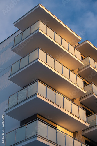 The building is a new block of flats, two-storeyed with glass balconies from the outside against the sunset sky