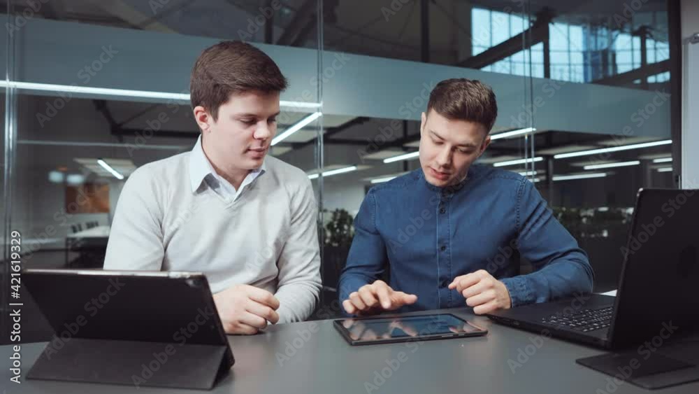 Men in office checking graphs and pie charts on tablet, laptops standing nearby. Managers discussing company progress. Business partners shaking hands when reaching agreement. Concept of collaboration Men in office checking graphs and pie charts on tablet, laptops standing nearby. Managers discussing company progress. Business partners shaking hands when reaching agreement. Concept of collaboration