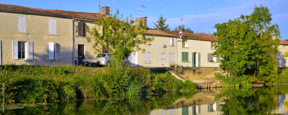 Fototapeta premium Panoramique Damvix (85420) se reflète dans la Sèvre Nortaise, département de Vendée en région Pays de la Loire, France