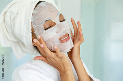 Mixed race woman wearing bathrobe and cleansing face mask in bathroom