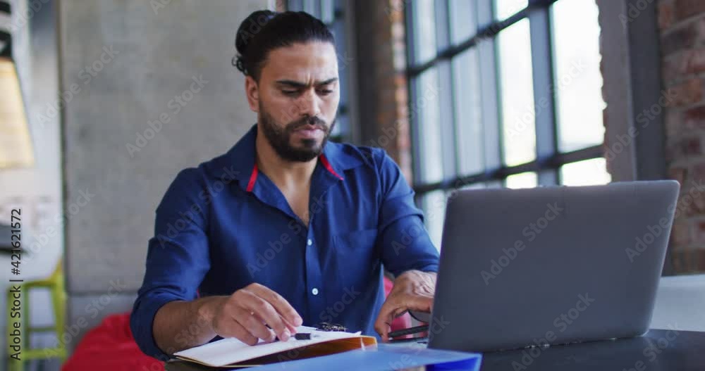 Happy mixed race man sitting in cafe using smartphone and laptop Happy mixed race man sitting in cafe using smartphone and laptop