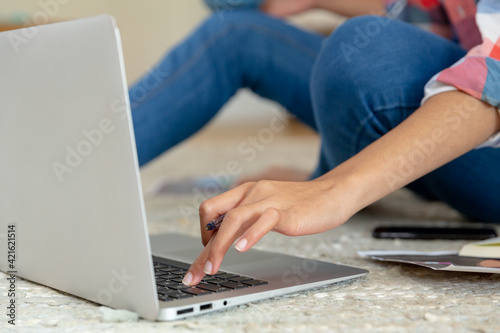 Mixed race woman sitting on the floor working from home using laptop