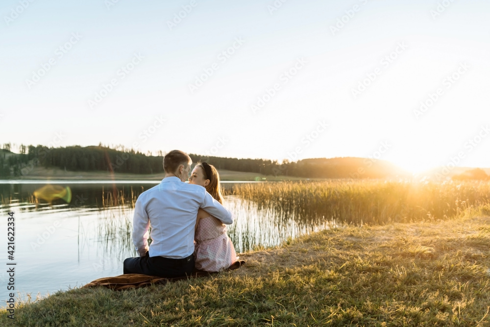 a young couple in love at sunset near the lake. a date in the park of a couple in love. the concept of romance and love.