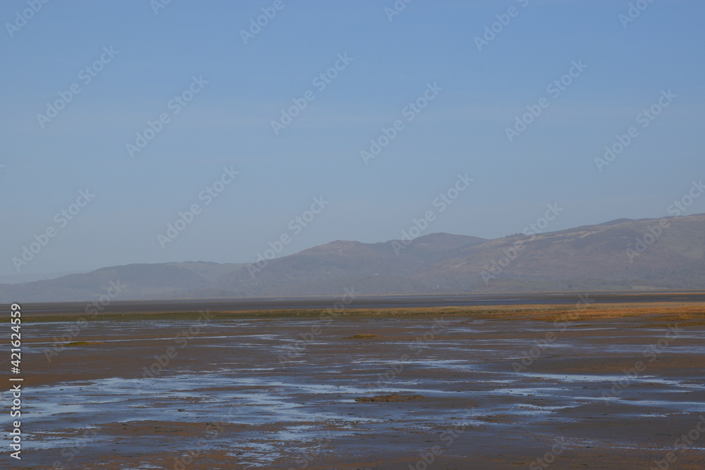 the smooth wet sand at the end of an estuary with the mountains in the background the smooth wet sand at the end of an estuary with the mountains in the background