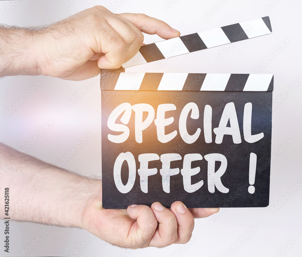 Obraz premium On a white background, a man holds a clapperboard in his hands on which it is written - SPECIAL OFFER