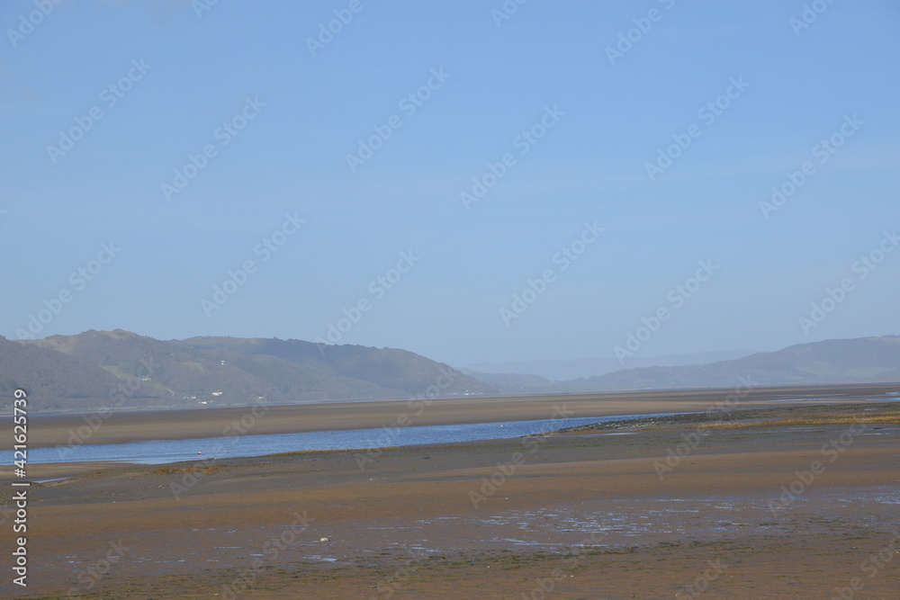 the smooth wet sand at the end of an estuary with the mountains in the background the smooth wet sand at the end of an estuary with the mountains in the background