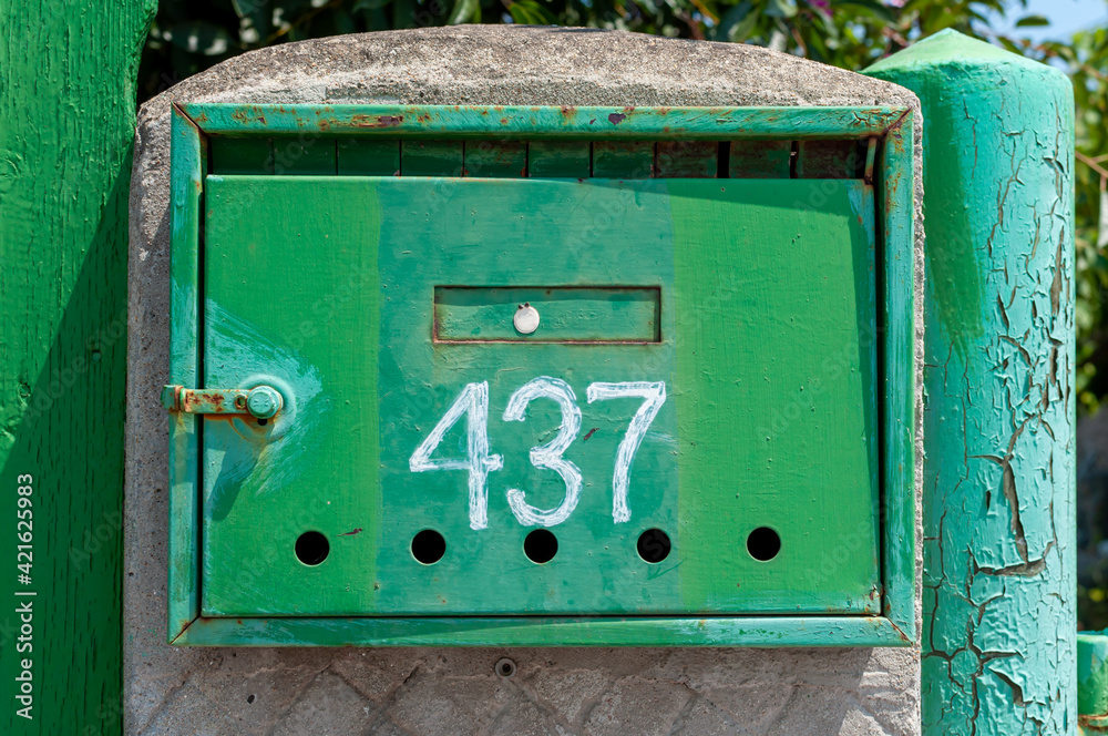 Close-up of a metal mailbox on a wall. Number 437.