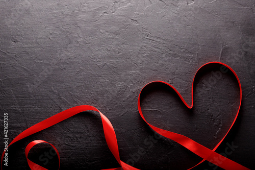 Happy Valentines Day. Red Ribbon on black stone background. Valentines Day concept